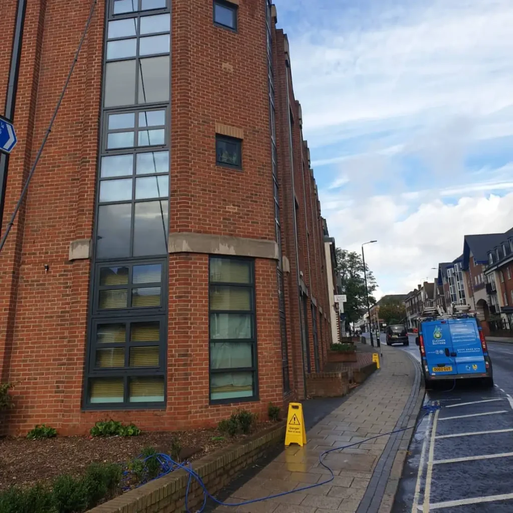 Water-fed pole cleaning upper-floor windows on a red-brick building